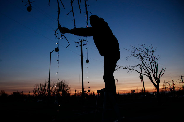 Travis Garrison hangs Christmas lights in his fire-ravaged Coffey Park neighborhood in Santa Rosa, Calif., Tuesday evening, Dec. 12, 2017. Garrison's family lost three homes in the deadly firestorm that swept through the tight-knit neighborhood two months ago. (Karl Mondon/Bay Area News Group)