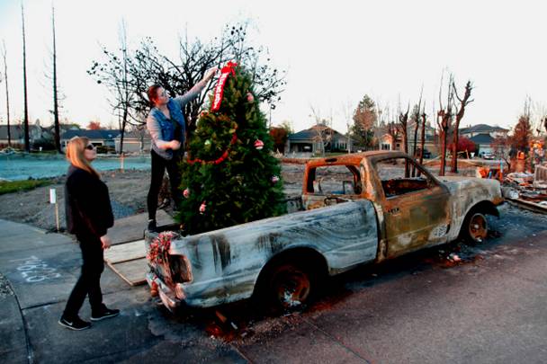 Nicole Medeiros and her daughter Caitlyn placed a Christmas tree, Tuesday evening, Dec. 12, 2017, in the bed of a neighbor's burnt-out truck in their firestorm-destroyed Coffey Park neighborhood of Santa Rosa, Calif. (Karl Mondon/Bay Area News Group)