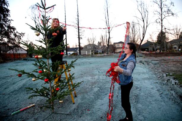 Nicole Medeiros and her daughter Caitlyn decorate a Christmas tree, Tuesday evening, Dec. 12, 2017, on the lot where their Coffey Park home stood before the deadly firestorm swept through Santa Rosa two months ago. (Karl Mondon/Bay Area News Group)