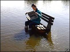 Девушка читает газету на скамейке в затопленном парке