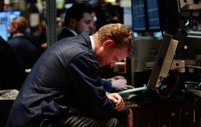 A trader hunches in front of his monitor on the floor of the ...