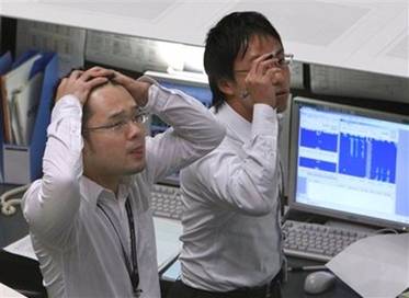 Stock traders on the Tokyo Stock Exchange gaze at digital indicator ...