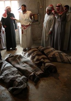 Syrian villagers stand near the bodies before a mass funeral ...