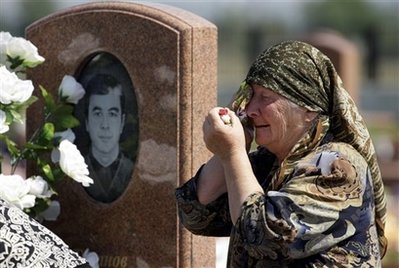 An elderly woman reacts, next to the grave of Batraz Tuganov, ...