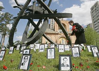 Родственник возлагает цветы у памятника погибшим в результате аварии на Чернобыльской АЭС