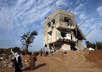 Жительница сектора Газа проходит около разрушенного дома на севере сектора Газа 