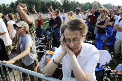 A woman closes her eyes in prayer as thousands ...